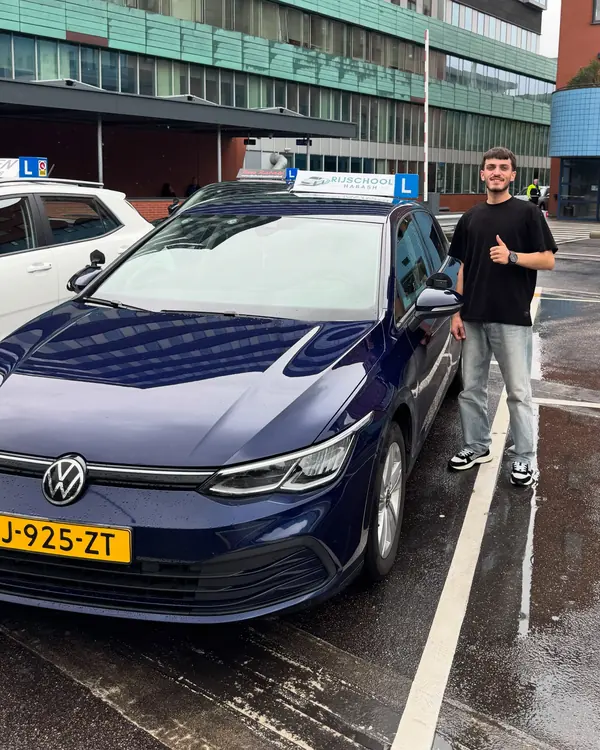 Geslaagde leerling steekt zijn duim op naast de lesauto van Rijschool Habash